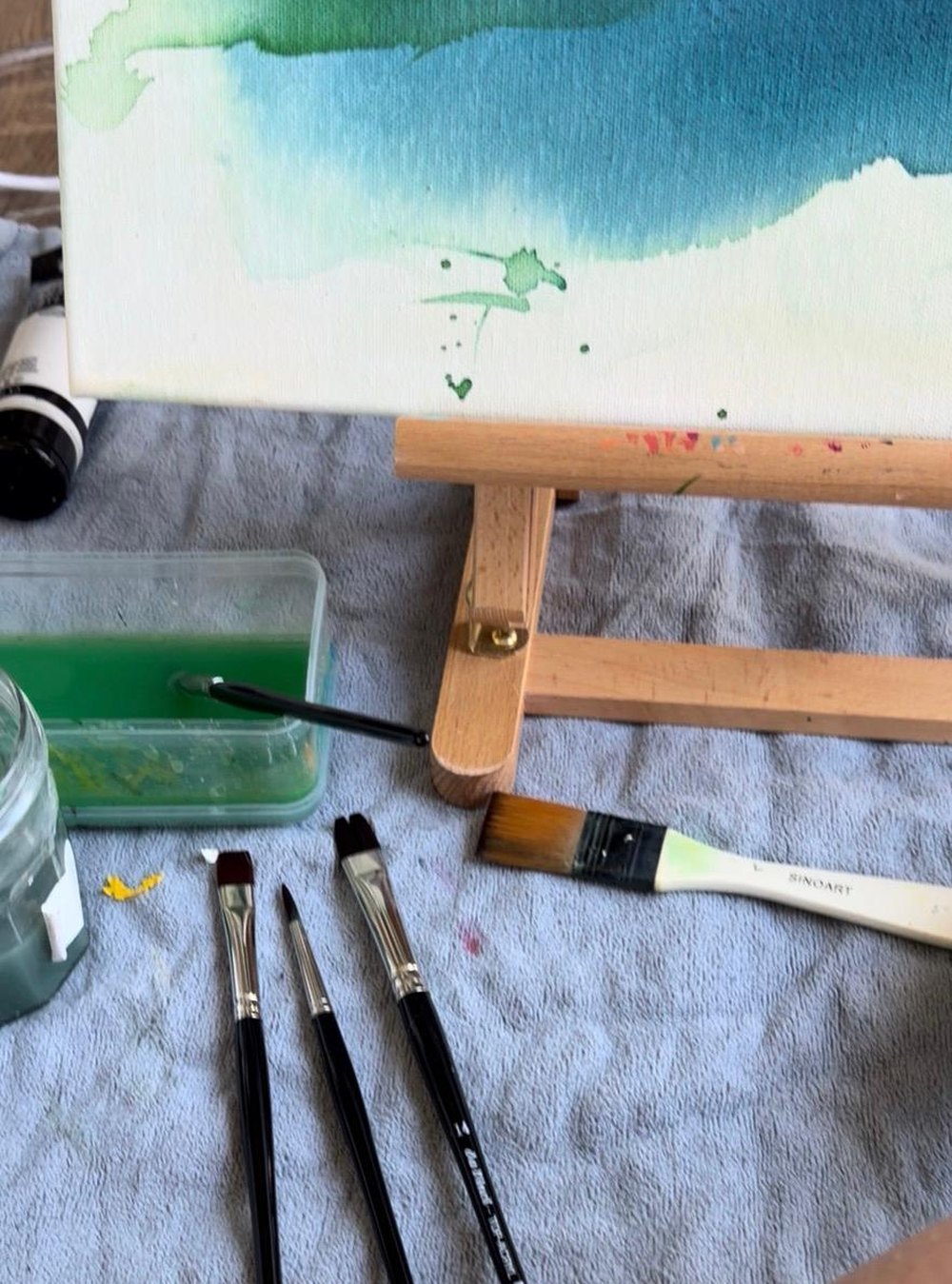 Atelier von Katja: Leinwand auf der Staffelei, Pinsel und Aquarellfarben